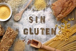 Gluten free flour and cereals millet, quinoa, corn flour polenta, brown buckwheat, basmati rice, bread and pasta with text gluten free in Spanish, language with spoon on brown wooden background,up view